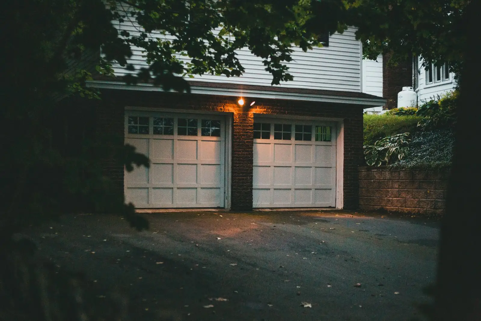 Two white garage doors lit at dusk